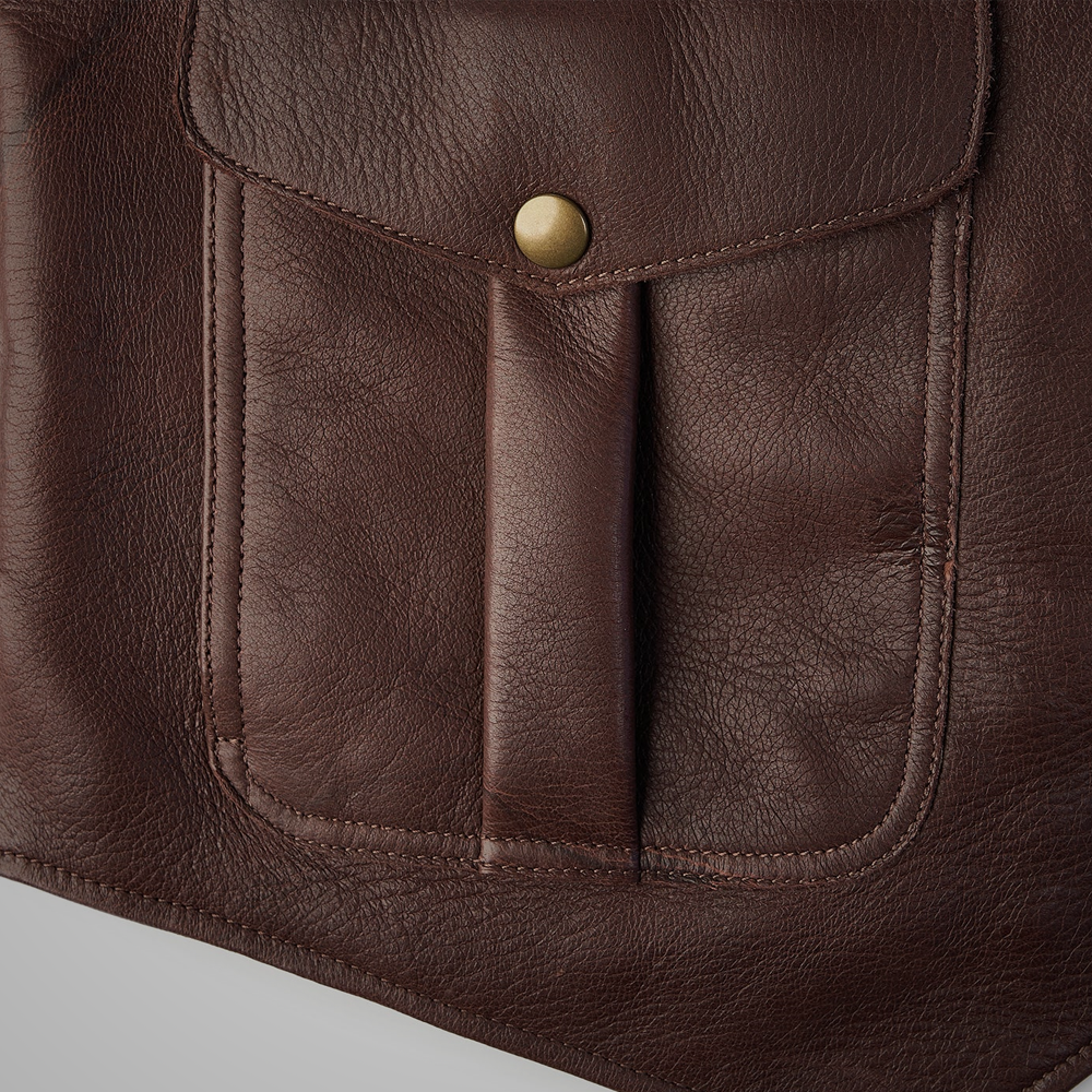 Close-up of a brown leather bag with a button on a light gray background