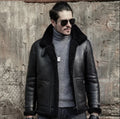 Man wearing a black leather jacket with fur collar and sunglasses against a textured wall.