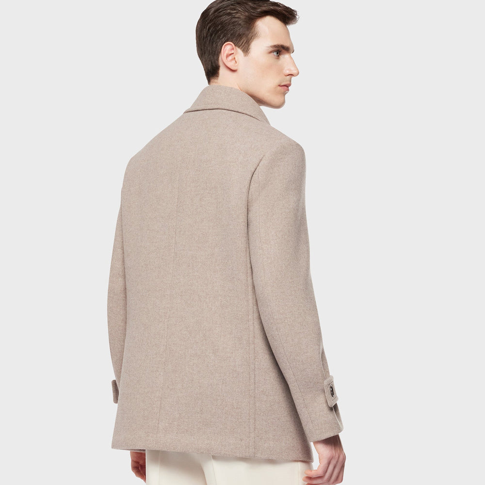 Man wearing a beige peacoat on a light gray background