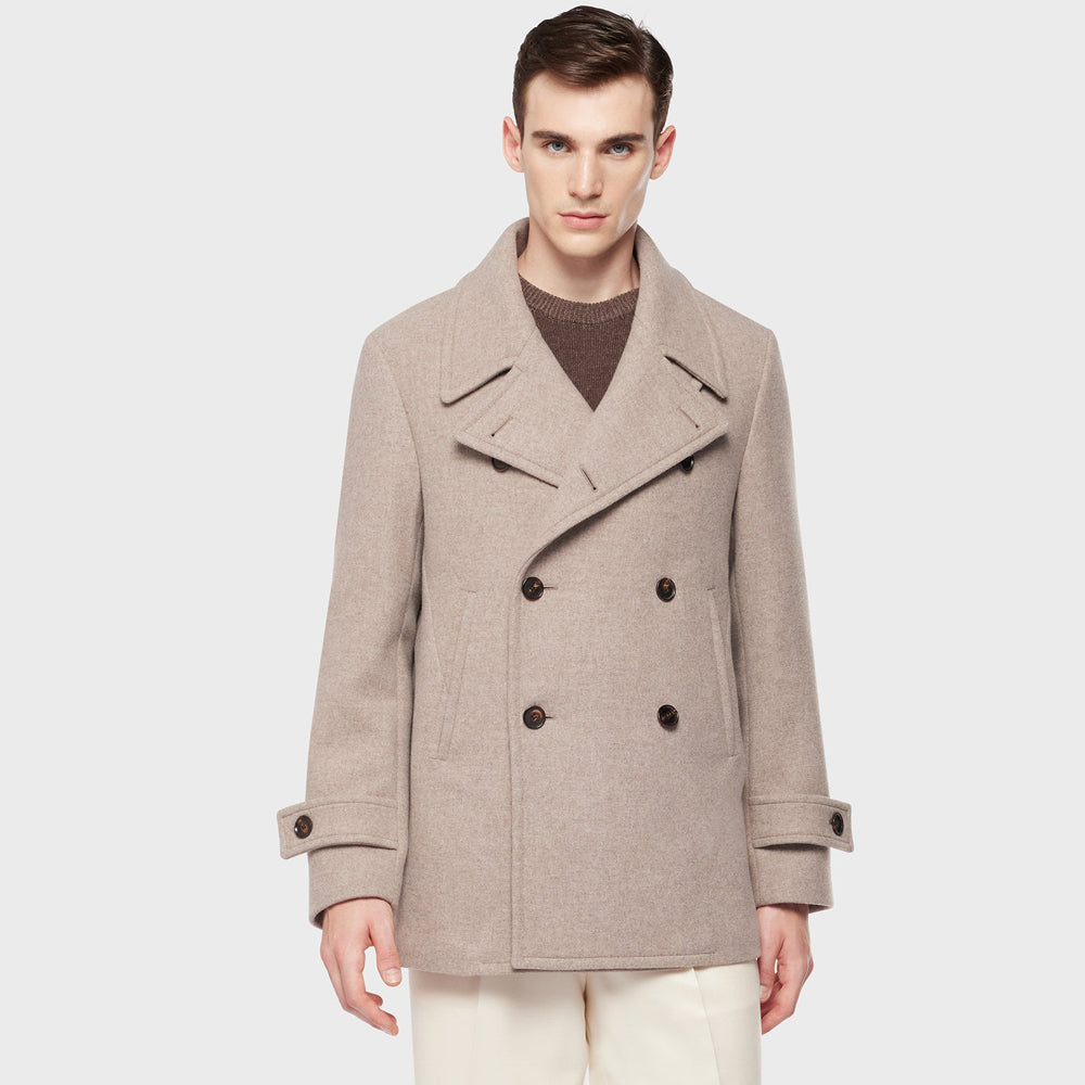 Man wearing a beige peacoat on a white background