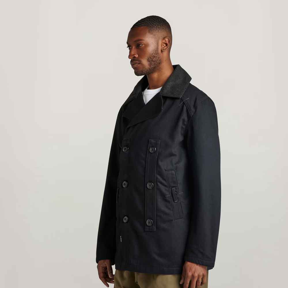 Man wearing a dark coat on a plain background